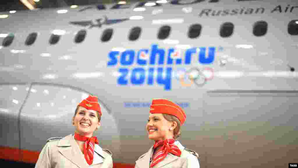 Aeroflot stewardesses stand in front of a passenger plane with the Sochi 2014 Winter Olympic Games logo in Moscow in May 2012.