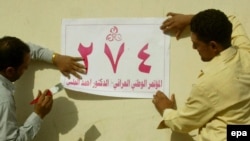 Iraqi men put up election posters on a street in Al-Najaf earlier this month.