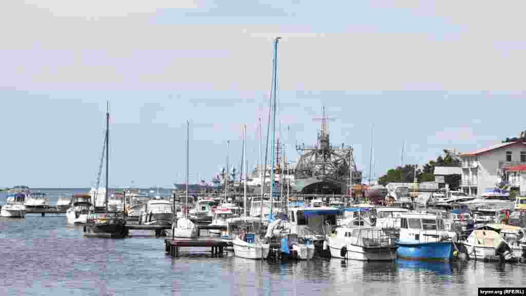 Стоянка яхт, яликів і рибальських човнів у Стрілецькій бухті. На задньому плані – кораблі Чорноморського флоту Росії