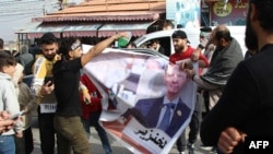 რეჟიმის დამხობით გახარებული მოქალაქეები ბაშარ ალ-ასადის ბანერს ხევენ