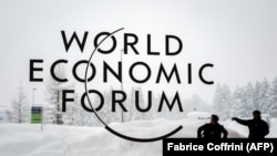 A security guard shows the way to a man outside of the Davos Congress Center under snow ahead of the opening of the World Economic Forum in January 2018.
