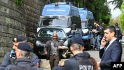 Чоловік з підносом із чашками та чайником проходить повз італійських поліцейських біля одного із входів до посольства Оману в Римі, 19 квітня 2025 року