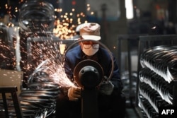 Рабочий полирует стальные обода для велосипедных колес на заводе по производству велосипедов на экспорт в городе Ханчжоу. Провинция Чжэцзян на востоке Китая