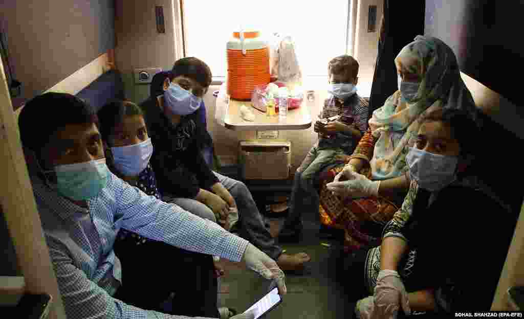 Masked passengers in Rawalpindi board a train on May 20. Authorities resumed railway service in Pakistan ahead of Eid al-Fitr after a two-month suspension.