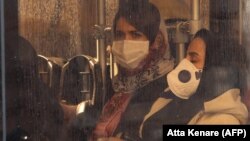 شهروندان در تهران در حالی که صورت خود را با ماسک و دستان خود را دستکشهای پلاستیکی پوشاندهاند سوار بر اتوبوس؛ ایران یکی از کانونهای اصلی شیوع ویروس کرونای جدید در خارج از کشور چین است.