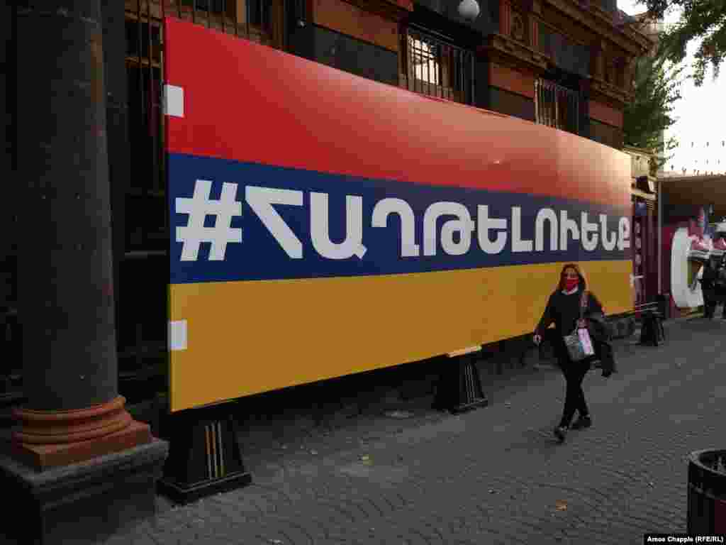 A woman walks past a large Armenian flag with the hashtag "we will win" on October 28. 