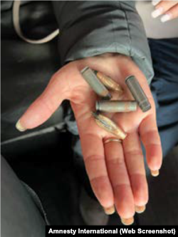 Дружина Євгена Петрашенка тримає кулі та гільзи, знайдені в будинку в Бучі, де вбили Євгена Петрашенка. Фото Amnesty International зі звіту «Він не повернеться». Воєнні злочини в північно-західних районах Київської області