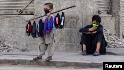 A young boy sells face masks on a stick in Karachi.