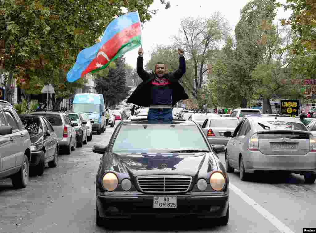 A man in Baku joins crowds celebrating in the Azerbaijani capital after President Ilham Aliyev claimed on November 8 that his forces had captured the city of Shushi/Susa. 