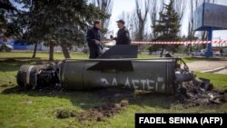 Українські силовики біля фрагмента ракети «Точка-У» з написом російською мовою «За детей» після ракетного удару російськими військами по залізничному вокзалі в Краматорську, 8 квітня 2022 року