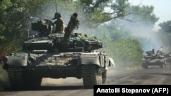 Украинские военнослужащие едут на танках по дороге в Луганской области, 21 июня 2022 года