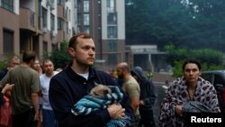 Locatarii unui bloc din Kiev lovit de ruși se „regrupează” în fața clădirii, luni, 21 iulie.