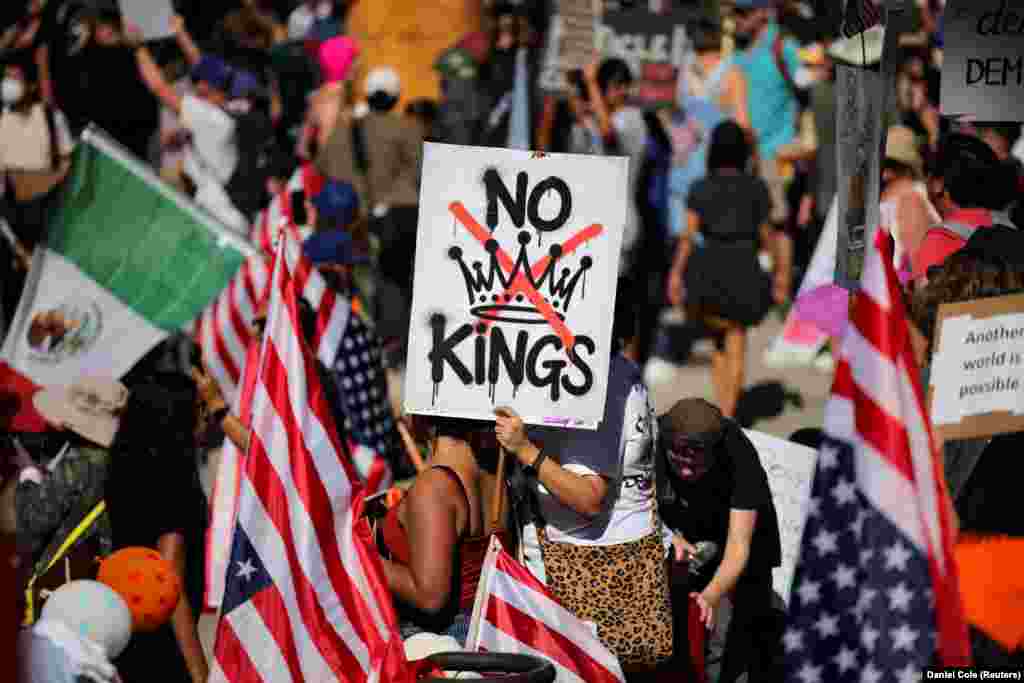 Участник акции протеста держит плакат с надписью NO KINGS с перечеркнутой иллюстрацией короны во время акции протеста "Нет королям" против политики президента США Дональда Трампа у здания мэрии в Лос-Анджелесе, Калифорния, США, 18 октября 2025 года. REUTERS/Daniel Cole