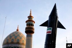 Модель іранської ракети проносять поруч з мечеттю в Тегерані. 15 квітня 2024 року