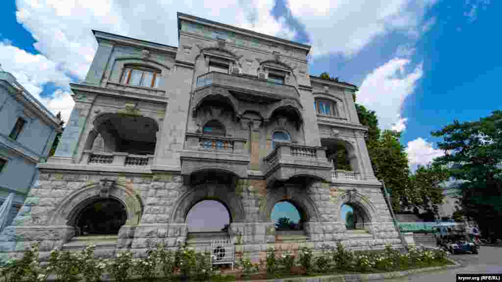 Дом барона Фредерикса находится между корпусом санатория «Ливадия» (слева) и дворцом-музеем. Официальное название до 1917 года – «Министерский дом с квартирами фрейлин». Трехэтажное здание выдержано в стиле «прибалтийского модерна». Владимир Фредерикс – министр императорского двора Российской империи. Доверенный сановник регулярно сопровождал Николая II во всех поездках, в том числе в Ливадию