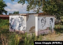 Обществена тоалетна с принцеса Даяна и обезличен портрет на Ангела Меркел. До тях са нарисувани местни жители.