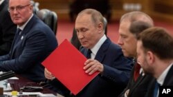 Presidenti rus, Vladimir Putin, me një dosje të kuqe.