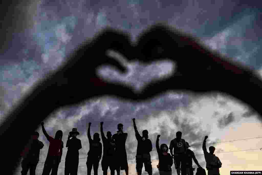 Люди піднімають руки та вигукують гасла, протестуючи біля імпровізованого меморіалу на честь Джорджа Флойда в Міннеаполісі, штат Міннесота