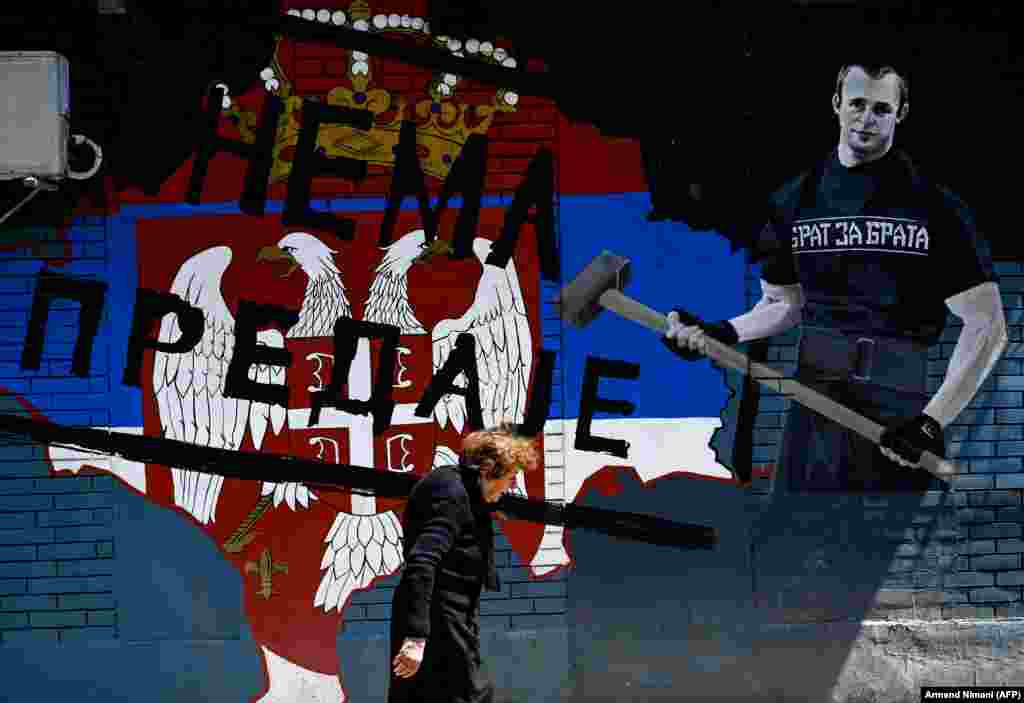 Женщина проходит мимо надписи «Сдаться нельзя» на улице в преимущественно сербской части города Митровица в Косово