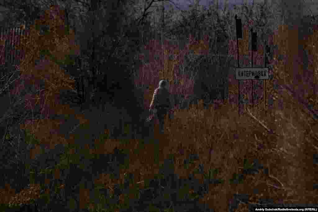 Доступ до Катеринівки можливий як на транспорті, так і пішки. Село починається за сотню метрів від КПВВ. На фото – жінка з торбами йде з Золотого у тепер уже «напівсіру» Катеринівку