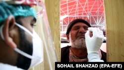 په اسلام اباد کې یو روغتیاپال د کورونا وایرس معاینې لپاره د یو کس له پوزې مایع اخلي - پخوانی انځور.