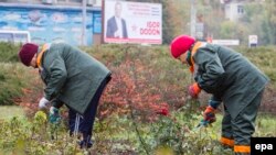 Two Moldovan women work against the backdrop of an electoral campaign poster for presidential front-runner Igor Dodon in Chisinau on October 27.
