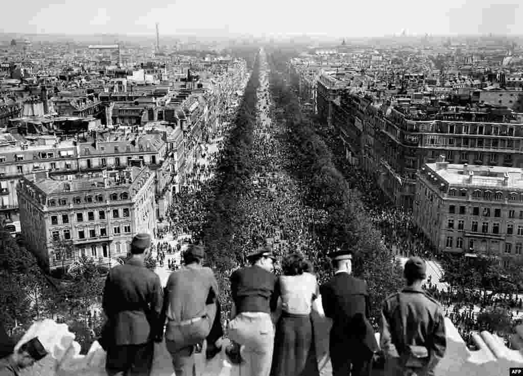 Paris, Franța, 8 mai 1945 - Oameni care privesc de pe Arcul de Triumf bulevardul Champs Elysees aglomerat – parizienii s-au adunat pe străzile orașului pentru a sărbători capitularea necondiționată a Germaniei la sfârșitul celui de-al doilea război mondial.