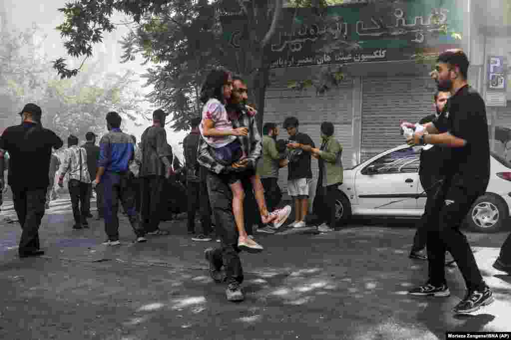 Iran, 15 iunie 2025. Un bărbat cară o fată rănită după o explozie în centrul Teheranului, care a urmat unor lovituri israeliene asupra unor ținte din Iran.