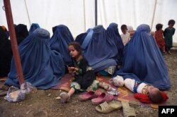 Afghan refugee women sit with their children after returning to Afghanistan from Pakistan, at the UNHCR camp on the outskirts of Kabul in September 2016.