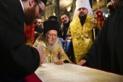 Вселенський патріарх Варфоломій підписує томос про автокефалію для Православної церкви України (ПЦУ). По ліву руку від нього стоїть митрополит Київський і всієї України Епіфаній. Стамбул, 5 січня 2019 року