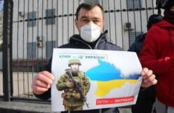 Плакат із зображенням президента Росії Володимира Путіна під час акції «Крим – це Україна» біля російського посольства в Києві, 16 березня 2020 року