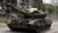 Российский танк, нагруженный вещами, едет по улице города Попасная в Луганской области, май 2022 г.