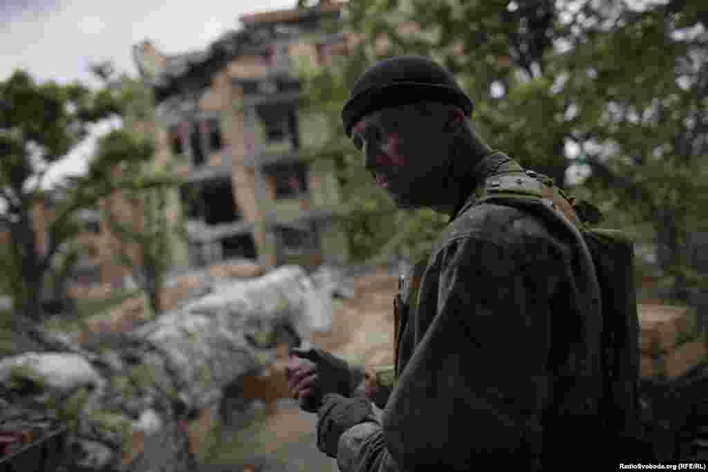 Сергій, ротний командир батальйону «Донбас», поруч із напівзруйнованим артилерією бойовиків санаторієм. Будівля служить укриттям і є крайньої позицією українських бійців