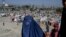 A burqa-clad woman stands by a displacement camp in Kabul on September 17.