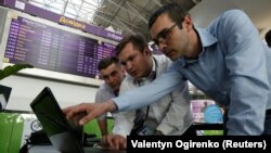 Technicians work on a flight timetable for the website of Ukraine's Boryspil Airport near Kyiv following a cyberattack on June 27 that started in Ukraine before spreading elsewhere.