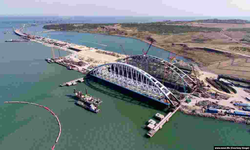 The twin 227-meter-long arches are prepared for placement. The arch on the left will support two railway lines, while the other will carry four lanes of automobile traffic. 