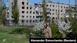 O femeie se întoarce de la biserică, după slujba de Paște, prin apropierea unui bloc distrus, în Avdiivka, în regiunea Donețk, o zonă a Ucrainei controlată de Rusia, 20 aprilie 2025.