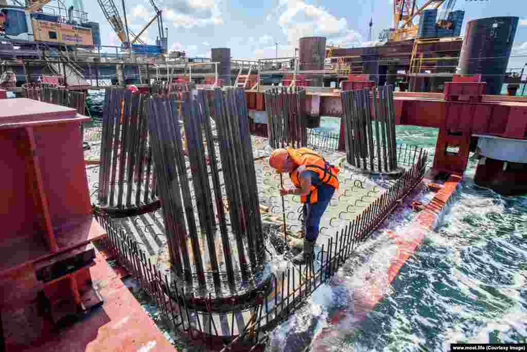 An engineer works as waves slap a pontoon. With the stakes high, Russian resources poured into the project. According to a New Yorker report, the building of new automobile roads in Russia was "practically suspended" while the Kerch bridge construction went ahead. 