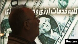 An Iranian man walks past a currency-exchange shop in northern Tehran. Sanctions on Iran have caused the rial to plunge in value, driving up the cost of imports.