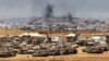This picture taken from a position in southern Israel on the border with the Gaza Strip shows Israeli tanks and bulldozers deployed as smoke billows over destroyed buildings in Gaza during Israeli bombardment on May 17, 2025.