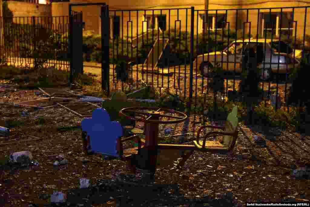 Bucăți dintr-o clădire sunt vizibile peste un loc de joacă din Kiev, după ce o explozie a zguduit un bloc de apartamente în timpul atacului rusesc cu rachete balistice și drone.