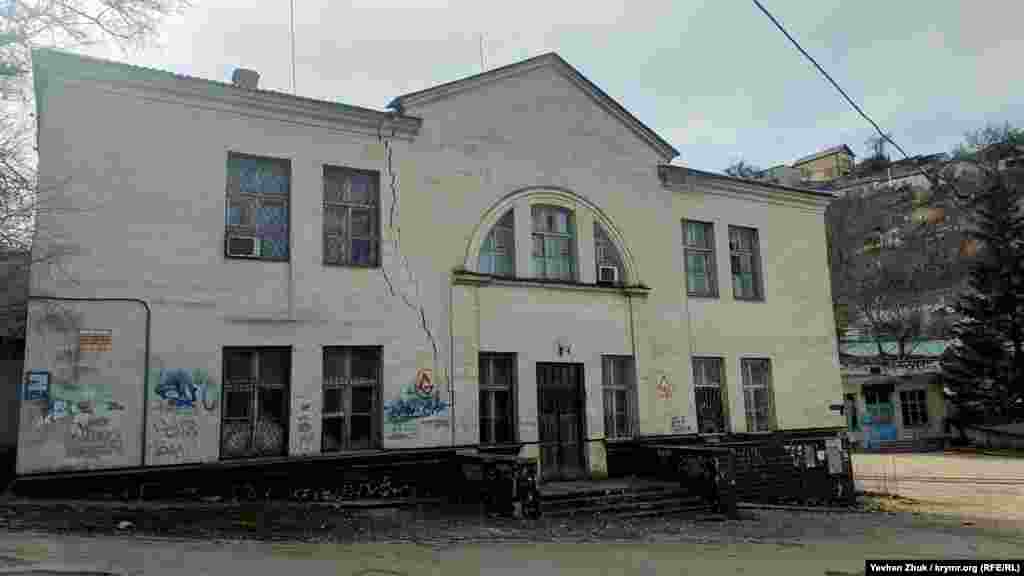 На площі перед прохідною – будівля, що буквально розвалюється, фанерована альмінською плиткою. Можливо, це був заводський клуб або просто адміністративна будівля