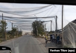 Сетка над шоссе возле Константиновки Донецкой области. Вправо на снимке видна очередь в магазин – местные жители тоже защищены сеткой от ударов дронов, 16 сентября