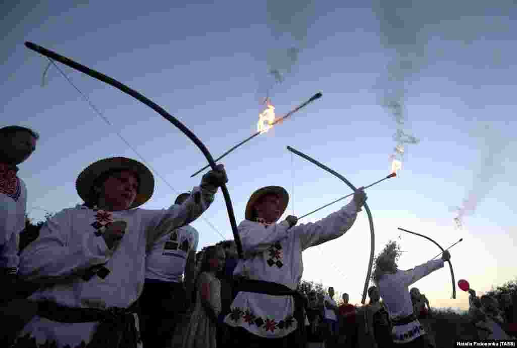 Чоловіки в етнічних білоруських  костюмах випускають палаючі стріли під час урочистостей Івана-Купала