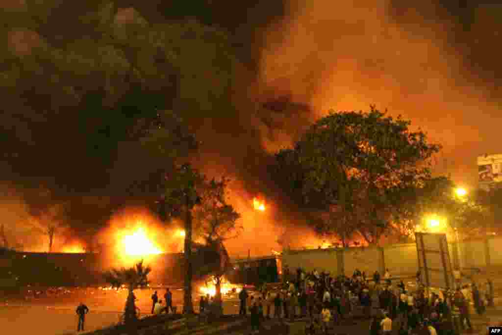 Egyptians gather around the burning headquarters of the ruling National Democratic Party in Cairo on January 28, 2011.