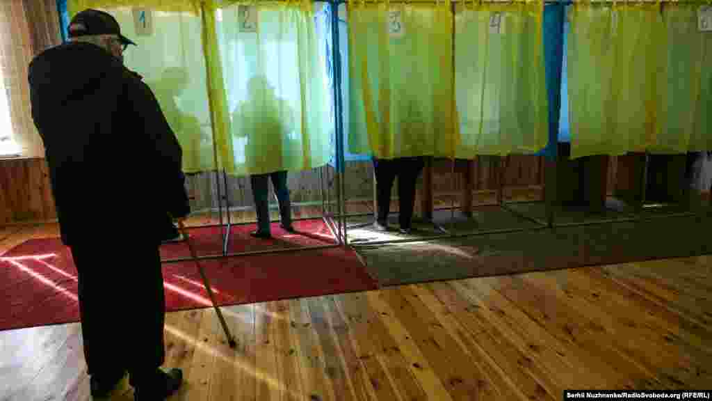 Чоловік очікує своєї черги, щоб зайти до кабінки голосування  