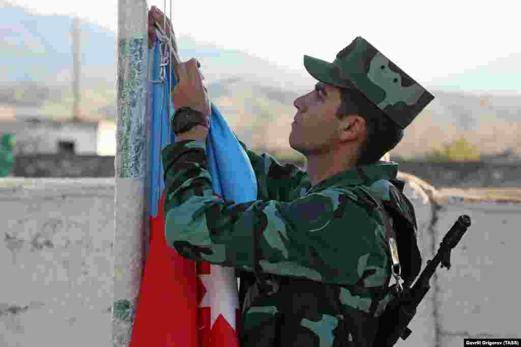 An Azerbaijani soldier hoists his country's flag during a ceremony in the village of Mincivan, which was recently taken from Armenian forces. 