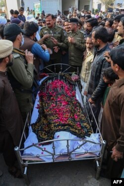 Relatives, locals, and police officers stand near the Mushtaq's coffin on February 13.