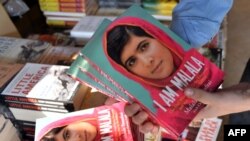A bookstore employee poses with copies of the memoirs of Pakistani child activist Malala Yousafzai in Islamabad.