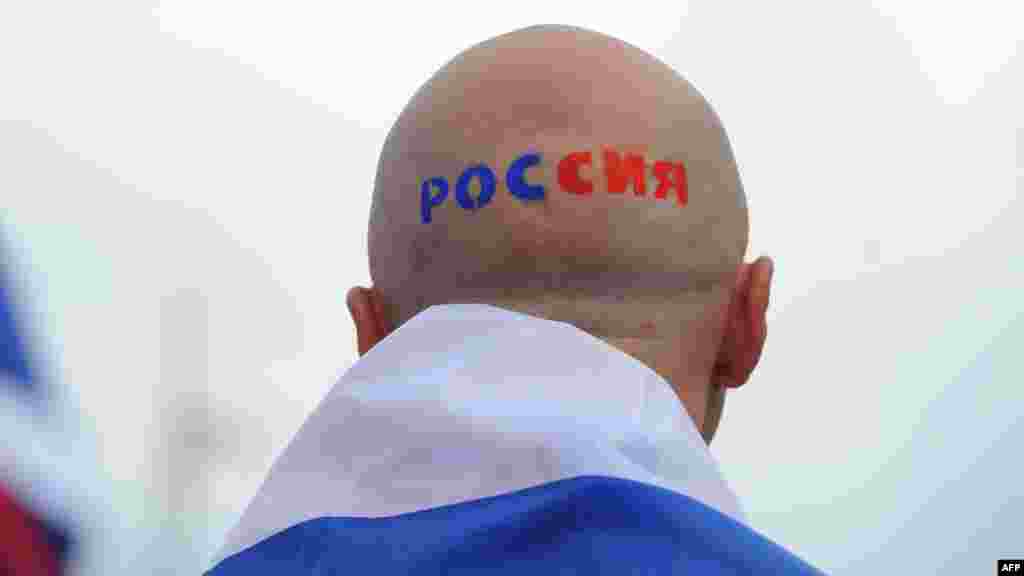 A Russian football fan with "Russia" painted on his head outside the stadium in Warsaw